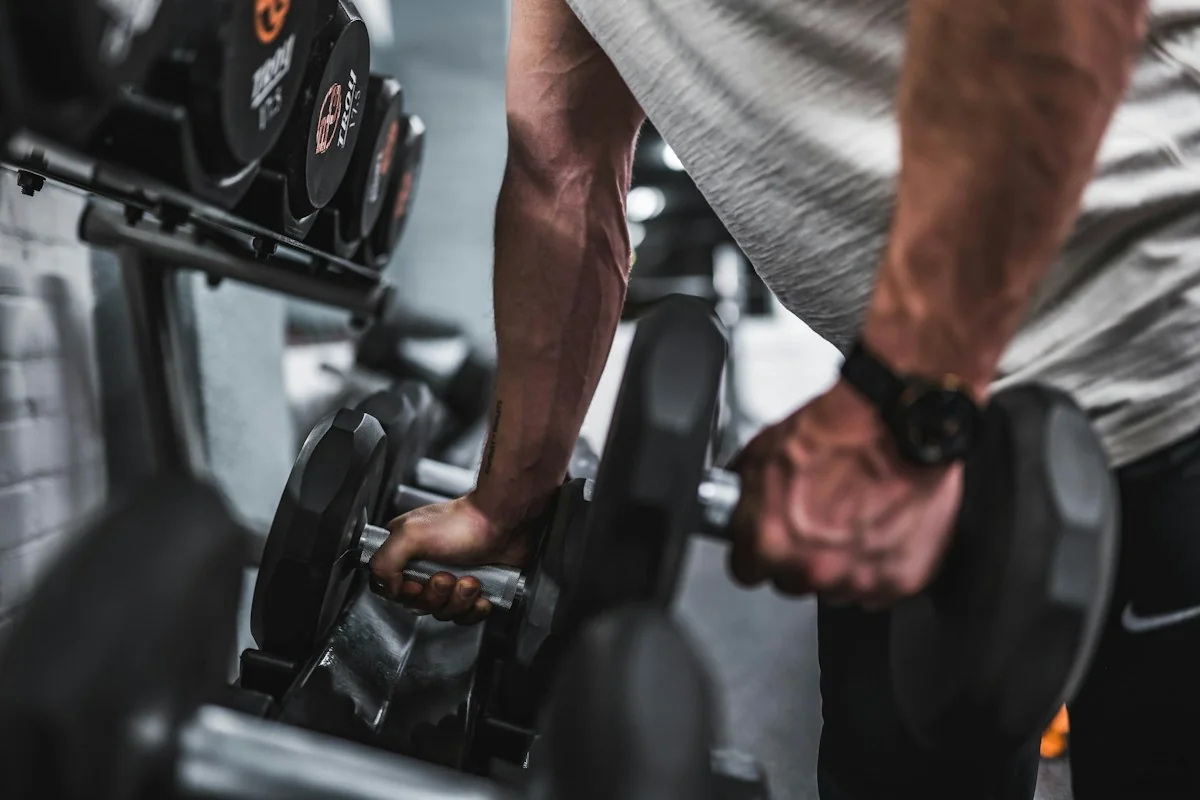 Primer plano de una persona sujetando mancuernas en el gimnasio.